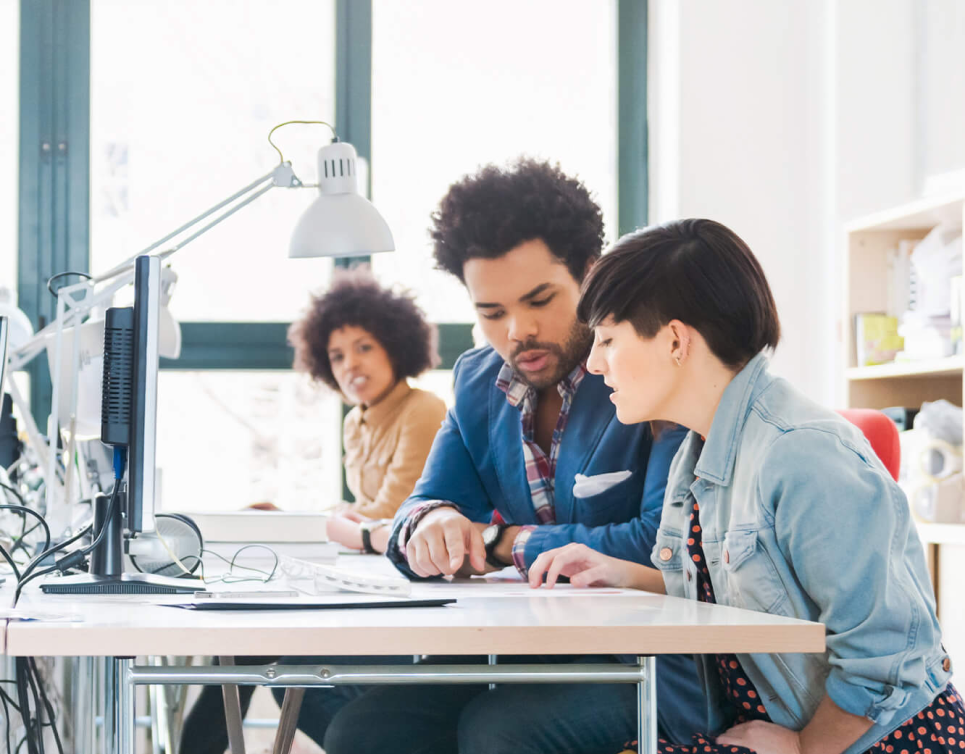 Three people sit in the office and work