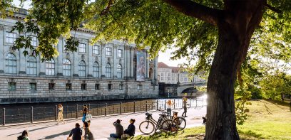 Picture from the banks of the Spree. People sit on the grass and look out over the Spree